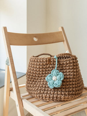 Beige crocheted nursery storage basket with flower detail on a wooden chair – Anzy Home