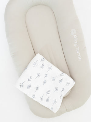 White leaf-print muslin cover on an ivory baby lounger nest – Anzy Home