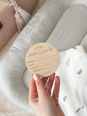 Wooden baby birth announcement disc on a muslin-draped lounger – Anzy Home