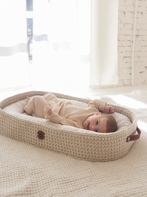 Baby resting in a beige crocheted XL lounging and changing basket – Anzy Home